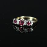 A three stone ruby ring interspaced with diamonds,
