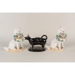 A pair of Victorian porcelain dogs holding baskets of pups plus a black glazed cow creamer (as