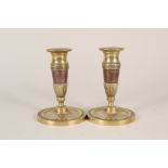 A pair of early 19th Century French brass and copper candlesticks with fluted and chased decoration,