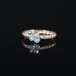 A yellow metal band ring with raised floral decoration to entire band with turquoise set clover to