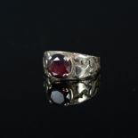 A 9ct gold ring set with single garnet with ornate embossed and engraved shoulders,