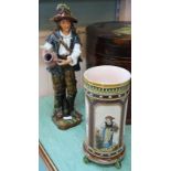 A German pottery figure of a boy and urn plus a 19th Century Mettlach figure painted vase (cracked)