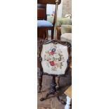 An ornately carved Victorian pole fire screen with floral tapestry