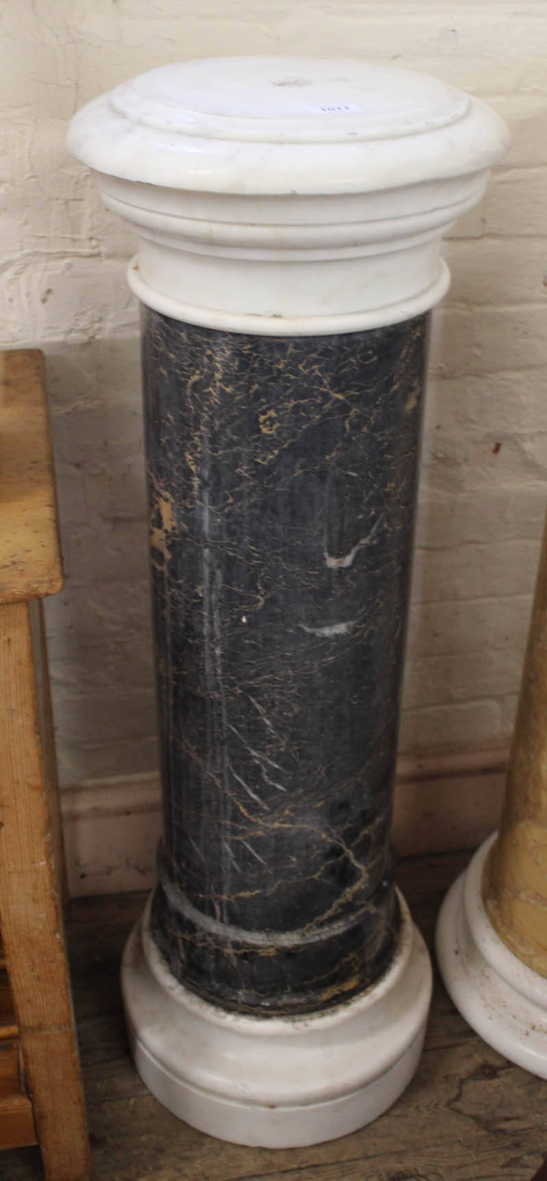 A black marble column with white marble top and base