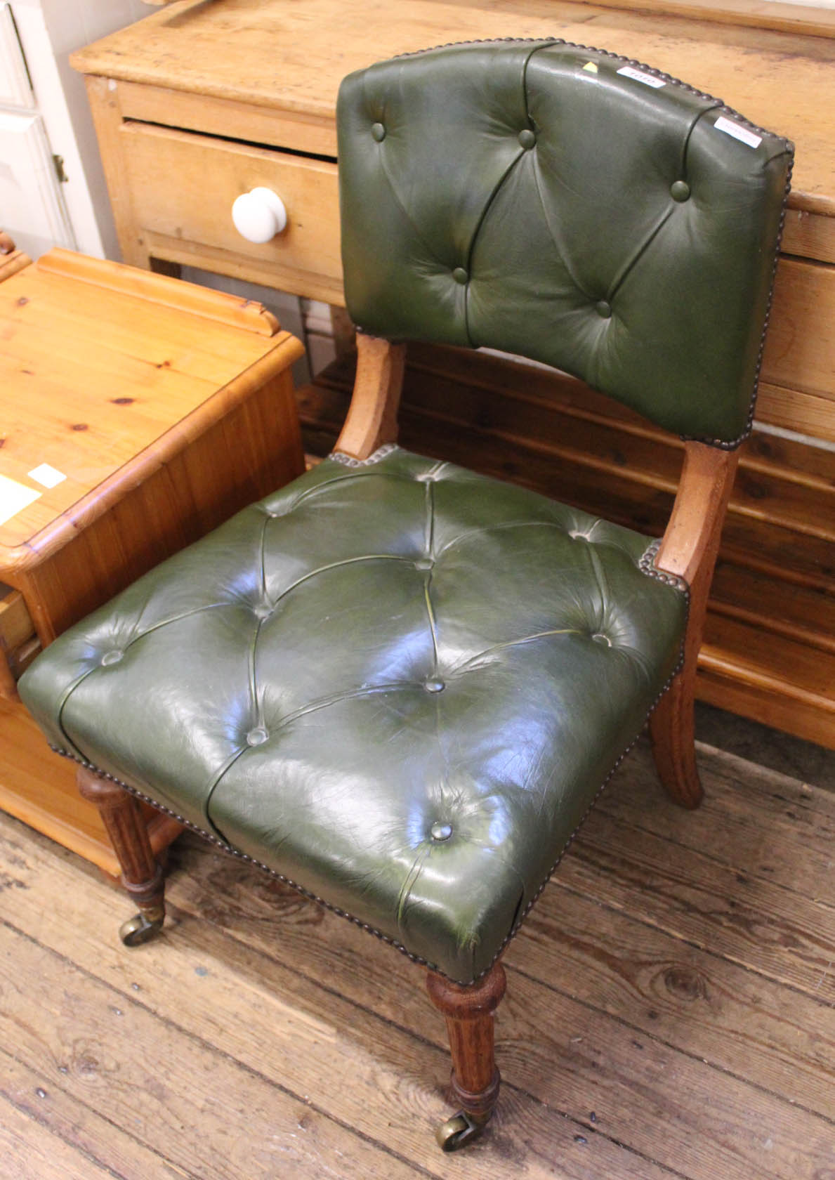 An Edwardian oak frame lounge chair with green leather button back upholstery