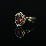 A 9ct gold ring set with garnet and floral border,