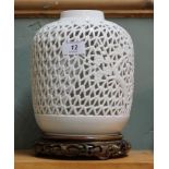 A Chinese white porcelain reticulated vase on carved wooden stand,