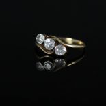 An 18ct gold three stone diamond crossover ring, the three old cut diamonds in rubover setting,