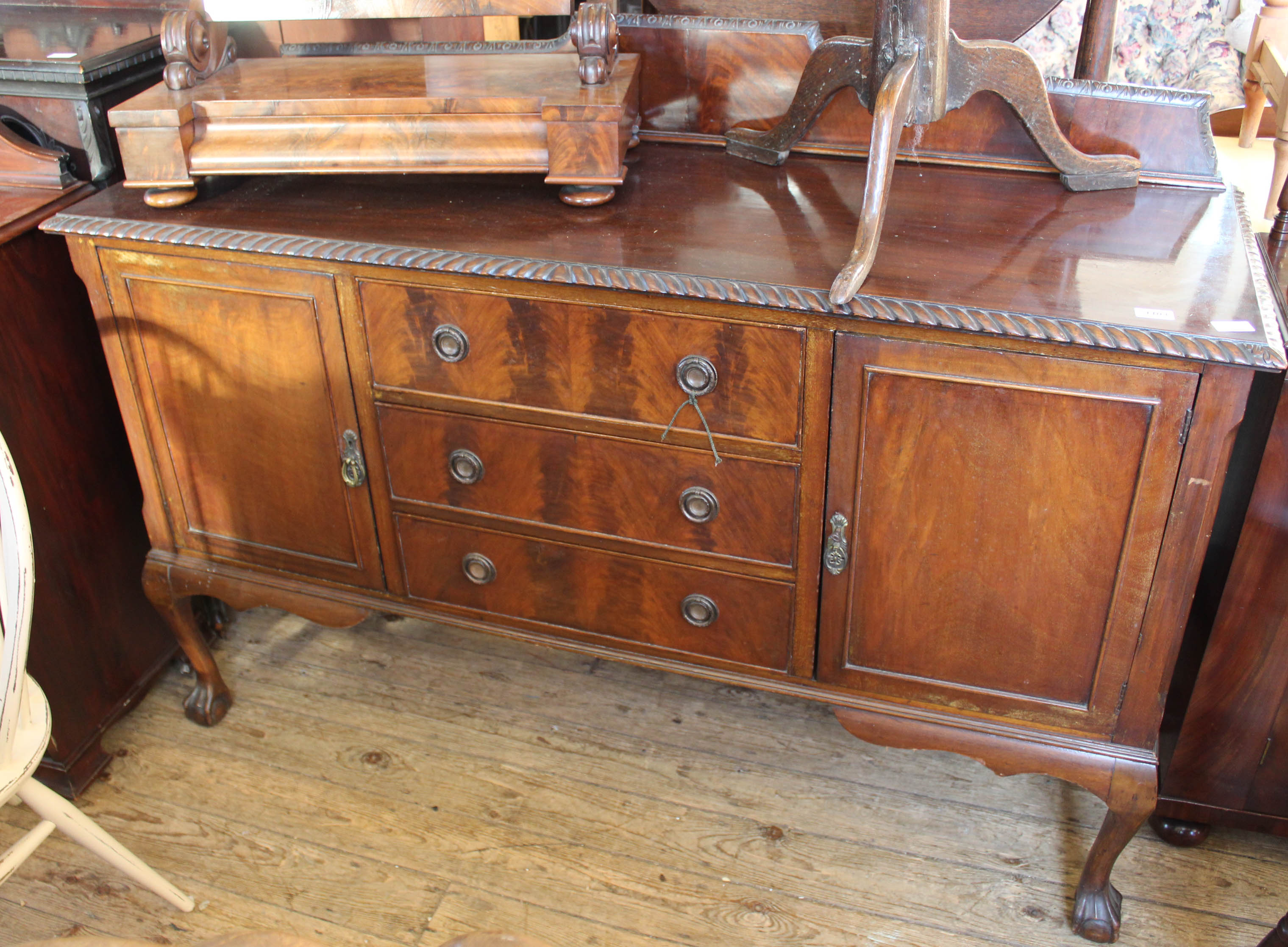 An Edwardian carved mahogany sideboard with three drawers and two doors on cabriole legs