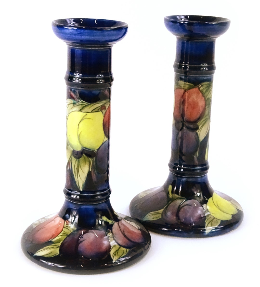 A pair of Moorcroft Wisteria pattern candlesticks, on a cobalt blue ground, impressed and hand