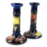 A pair of Moorcroft Wisteria pattern candlesticks, on a cobalt blue ground, impressed and hand