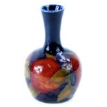 A Moorcroft Pomegranate pattern bottle shaped vase, decorated with fruit, on a cobalt blue ground,