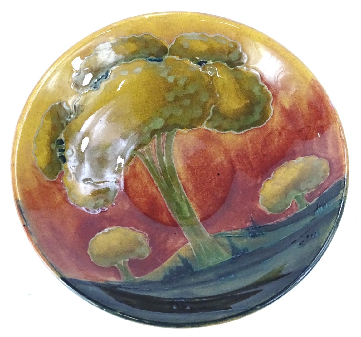 A Moorcroft Eventide pattern saucer, decorated with trees, with a red sky etc., impressed mark to