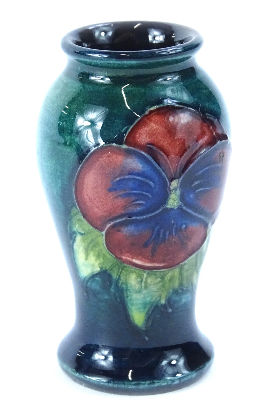 A Moorcroft miniature pottery vase, decorated with two pansies on a turquoise ground, impressed mark