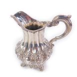 A Victorian silver cream jug, the fluted body with a band of embossed roses shamrocks and