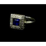 An Art Deco dress ring, with central square cut sapphire, surrounded by tiny diamonds, on a white