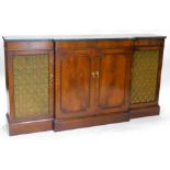 A mahogany breakfront sideboard, in regency style, with a green marble top above two panelled doors,