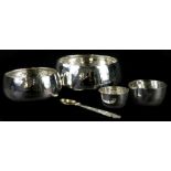 A graduated set of four hammered white metal Eastern bowls, of plain form and a spoon with