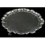 A George V silver waiter, with a pie crust border, on scroll feet, London 1911, 14¾oz, 23cm dia.