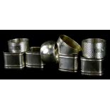 A collection of silver and silver plated napkin rings, the three silver examples, each with engine