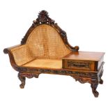 An Eastern hardwood telephone seat, with a caned back and seat, the frame carved with scrolls,