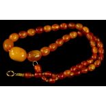 A butterscotch amber beaded necklace, of graduated form, on string strand, 39cm long overall, 9.5g