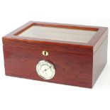 A glazed and veneered cigar humidor, the hinged lid enclosing various divisions, the front mounted