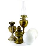 Three brass oil lamps, one with frosted shade, decorated with stars etc., another opaque