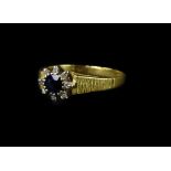 An 18ct gold sapphire and diamond cluster ring, with central round brilliant cut sapphire and tiny