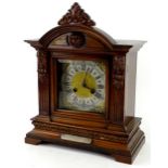 A German mantel clock, in a walnut case, the crest decorated with a lion mask above a squared
