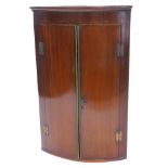 An early 19thC mahogany and chequer banded bow fronted corner cabinet, with two plain doors, 103cm