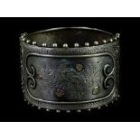 A Victorian aesthetic silver bangle, with tricolour design leaves and flowers on central panel, with
