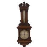 A late Victorian oak aneroid wheel barometer by Maple & Co, of architectural form, having an urn and