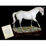 A 20thC Royal Doulton figure of Desert Orchid, on naturalistic base and wooden plinth, matt, with