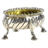 A Victorian silver oval salt, with part fluted border on four scroll feet and gilt interior,
