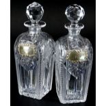 A pair of square section cut glass decanters and stoppers, each with a silver label for Gin and