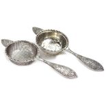 Two similar silver tea strainers, each decorated with rococo scrolls etc., one with a fine mesh