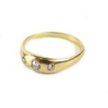 A three stone set diamond gypsy ring, with three old cut diamonds, each in rub over setting, the