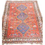 A Persian design rug, with a central pole medallion in blue, on a red ground with multiple