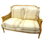A modern beech bergere two seat sofa, with cream and floral fabric, on turned fluted legs, 127cm W.