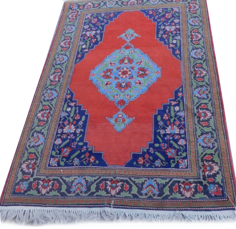 A Persian type rug, with a central blue medallion, on a red ground, with navy spandrels, one wide