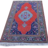 A Persian type rug, with a central blue medallion, on a red ground, with navy spandrels, one wide