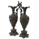 A pair of late 19thC Continental cast iron ewers, each decorated in renaissance style with masks,