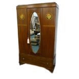 A 1920's mahogany wardrobe, with a moulded cornice, above a mirrored door with oval bevelled