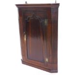 A late 18thC oak corner cabinet, with a moulded cornice above a door with an arched panel, flanked
