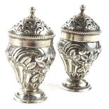 A pair of small Victorian silver salt pots, each with embossed decoration of scrolls, flowers