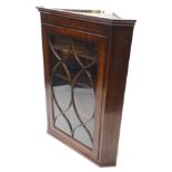A George III mahogany and ebony strung corner cabinet, with a moulded cornice, above a single