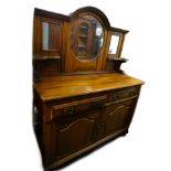 An early 20thC walnut sideboard, the raised back with a central circular bevelled mirror plate,