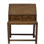 A George II oak bureau on stand, having fall flap resting on lopers, revealing an interior of