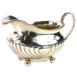 A George IV silver milk jug, with part fluted decoration, gadrooned border and gilt interior, on
